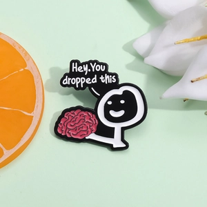 Cartoon brain enamel pin with stickman holding brain and 'Hey, You dropped this' text