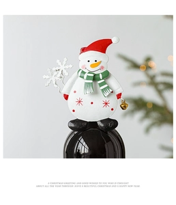 Detailed view of a white snowman wine bottle topper with red hat and green scarf decor
