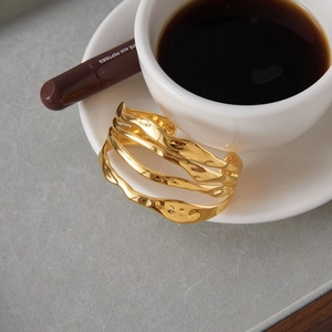 Minimalist 18K gold-plated stainless steel four-layer hollow cuff bangle on stone background