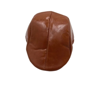 Detailed top view of caramel brown faux leather beret showing fine stitching and glossy finish