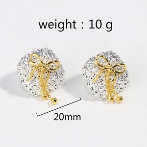 Detail view of square textured silver earrings with gold bow and hanging beads
