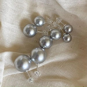 Macro shot of assorted grey glass pearl earrings in various sizes on burlap fabric background