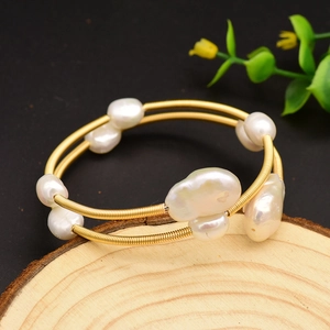Baroque freshwater pearl wrap bracelet with golden spiral wire on a rustic wood base
