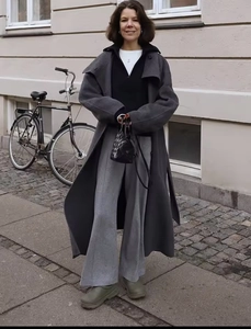 Outdoor street shot of women long dark grey wool coat with wide leg pants and ankle boots