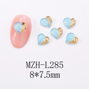 Macro detail of blue glitter and gold heart nail art charms on white background
