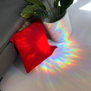 Rainbow light effect on red square pillow with shadows on floor and sofa background