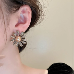 Detailed view of daisy-shaped earrings with rhinestones and champagne pearls