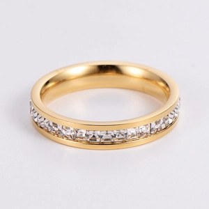 Detailed close-up of golden ring band set with sparkling white square cubic zirconia