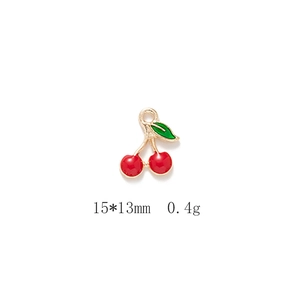 Detail of red cherry alloy pendant with gold plating and green enamel leaves for DIY jewelry