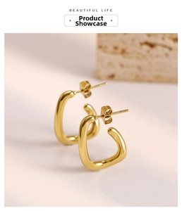 Macro view of polished gold U-shaped minimalist earrings on a natural stone base