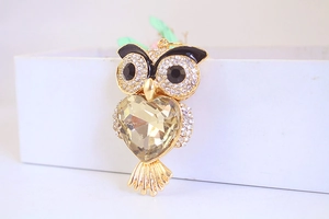 Macro shot of owl keychain featuring a large yellow heart crystal and sparkling rhinestones