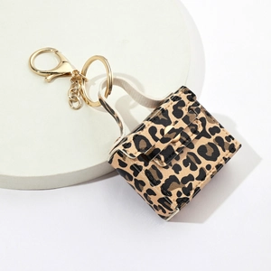 Mini leopard print PU leather bag keychain with gold metal clasp on white tray