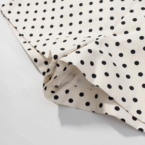 Detail der cremefarbenen Polka-Dot-Stofftextur und Saumnaht an lässigen Shorts