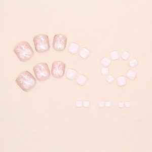 Detail of nude pink press-on toe nails with hand-painted white bows and glitter