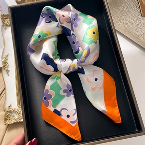 Close-up of silk square scarf featuring colorful floral checkers and satin texture