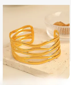 Close-up of a gold-plated multi-layer wave hollow bangle on a minimalist stone tray
