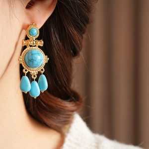 Close-up of vintage resin turquoise teardrop earrings worn by a model in soft lighting