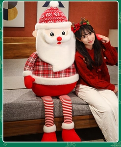 Large Santa Claus plush doll with long striped legs shown in a cozy bedroom setting