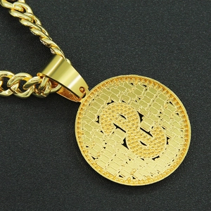 Close-up of golden hip hop dollar sign pendant and twisted chain on dark background