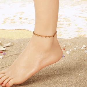 Golden beaded stainless steel anklet on a beach background for minimalist summer style