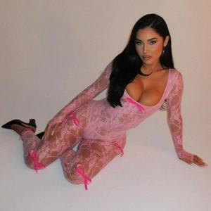 Detailed view of pink lace bodysuit featuring decorative bows and sheer floral texture