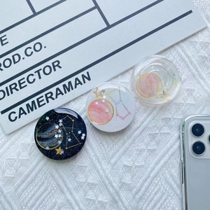 Three celestial-themed expanding phone grips with gold foil stars and galaxy patterns