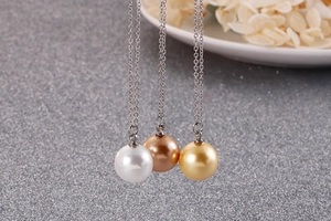 Détail des pendentifs perles et boules dorées sur colliers en acier titane argenté