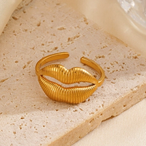 Adjustable gold lip-shaped ring with vertical texture on a minimalist stone display