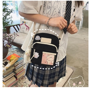 Détail du sac bandoulière noir avec broderie ours et pendentif mouton en peluche blanc