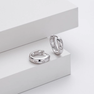Macro detail of S925 sterling silver huggie earrings with engraved stars and zircon inlay