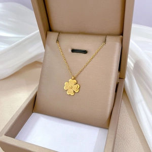 Elegant gold clover pendant necklace displayed on white silk inside a premium jewelry box