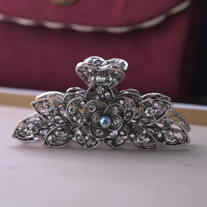 Macro view of silver floral hair claw clip with rhinestones and hollow-out leaf details