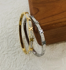 Detail of gold and silver stainless steel hinged bracelets with X-pattern and small crystals