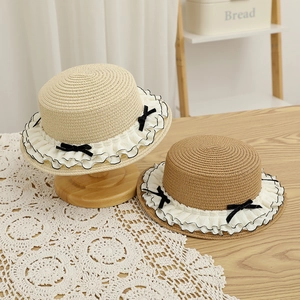 Detail of straw boater hats featuring white ruffled edges and black velvet bows