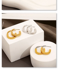 Close-up of geometric U-shaped earrings in gold and silver finish on artistic props