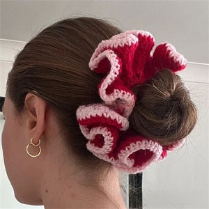 Detailed macro view of a handmade crochet ruffled hair scrunchie in red and pink yarn
