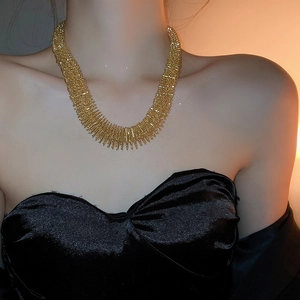 Close-up of golden wide choker necklace with textured spiked details on model