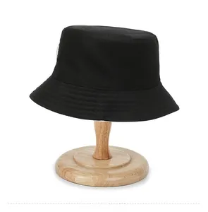 Rear view of a black cotton bucket hat with parallel stitched brim on a wooden stand