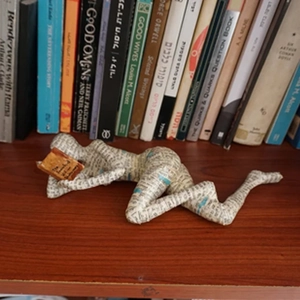 Macro detail of paper pulp reading woman sculpture with Winnie-the-Pooh text on wood shelf