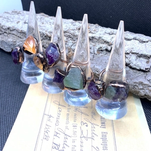 Detailed close-up of vintage raw amethyst and fluorite stones on adjustable bronze rings