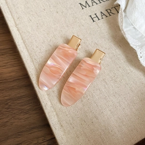 Close-up of pink marble texture hair clips on beige linen with elegant lace detail