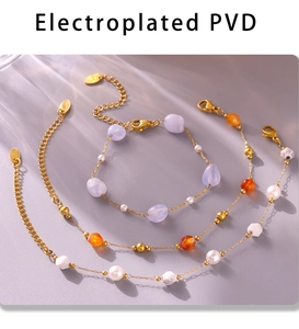 Three gold-plated PVD bracelets with purple, orange, and white beads on a grey surface
