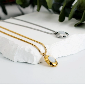 Macro shot of oval shell pendants on thin box chains in gold and silver finishes