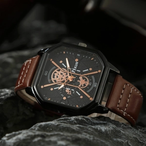 Macro view of men's square black watch with brown leather strap on dark rock background