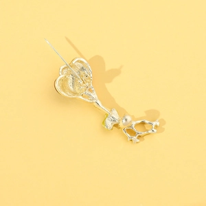 Détail du revers d'une broche dorée montrant le fermoir épingle et l'insert perle