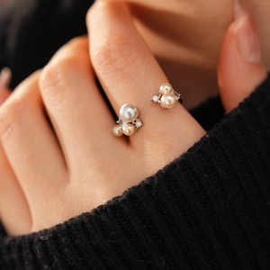 Close-up of elegant pearl ring with zircon accents on a hand wearing black knitwear
