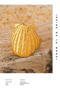 Detailed view of a golden seashell ring with ribbed texture on natural rock