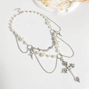 Detail view of silver layered necklace with cross and star charms on white background