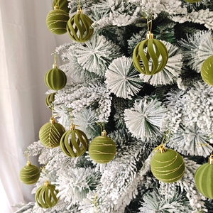 Détail de boules de Noël en velours vert avec motifs dorés sur un sapin décoré