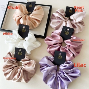 Detailed view of oversized satin scrunchies in various Morandi colors with handmade tags